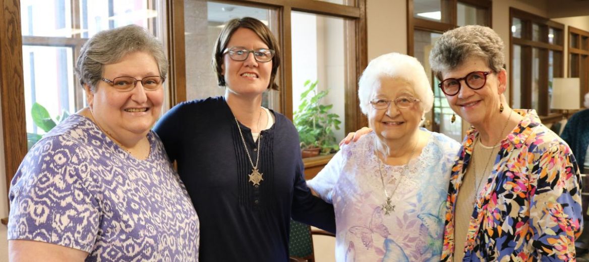 Four Franciscan Sisters of Perpetual Adoration pose arm in arm smiling
