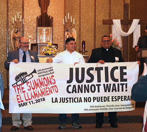  Presenters celebrate â€œThe Summonsâ€ at St. Bridgetâ€™s Catholic Church on May 11, 2018, holding a sign that says "Justice cannot wait! La justicia no puede esperar""