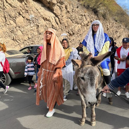 children dressed as mary and joseph from the nativity story process on a donkey during posada