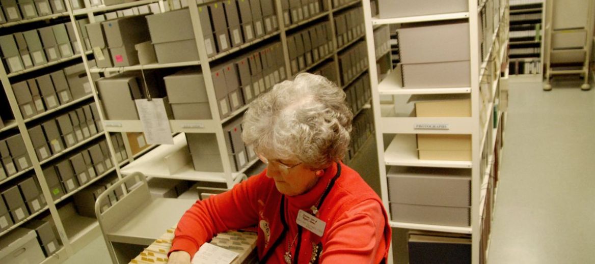 Sister Mary Ann Gscwhind looks through a card catalogue surrounded by boxes of historical information