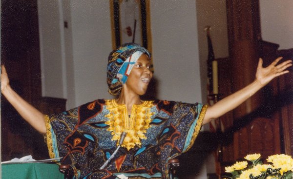 Sister Thea Bowman in bright colored garb with arms extended 