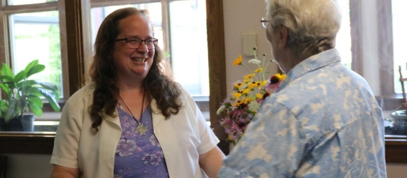 Sister Meg, smiling, is greeted in a receiving line by another sister
