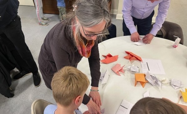 sister kristin peters teaches a child how to fold an origami fish as part of a campaign to raise awareness to the threats of the line 5 pipeline