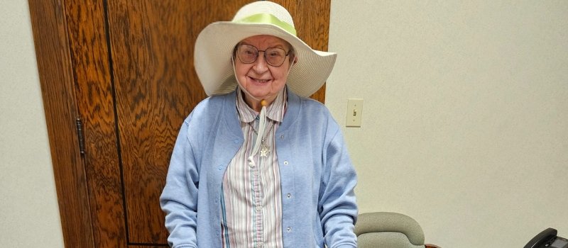 Sister Therese Wolf wearing a wide brim hat smiling for the photo