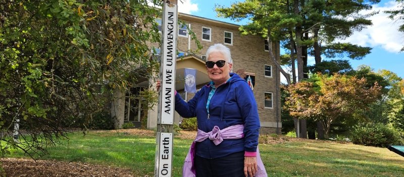 sister karen lueck poses in front of a peace pole