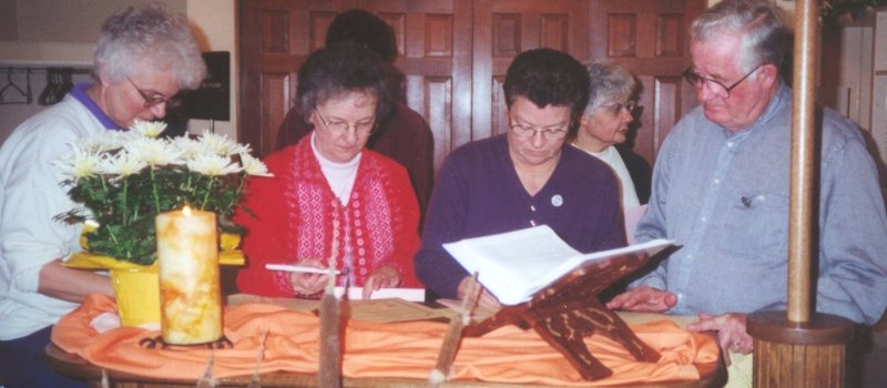 sister betty is pictured with three other people in front of a table and they are signing documents