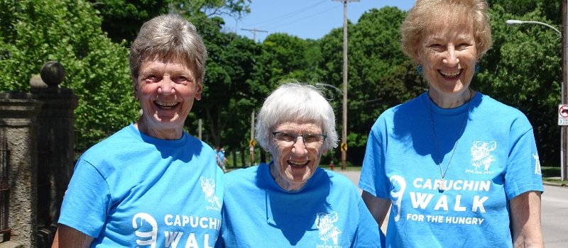 three catholic sisters from the sisters of st francis of assisi pose wearing blue tshirts promoting the capuchin walk for the hungry