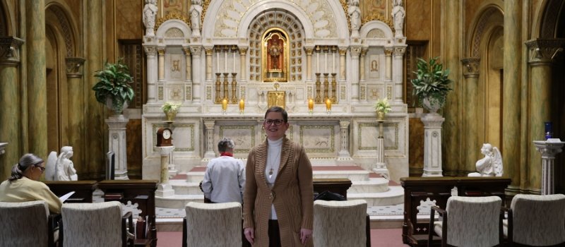 sister sue ernster stands in front of the perpetual adoration altar in front of two other women