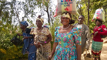 African woman carries bag of goods on head