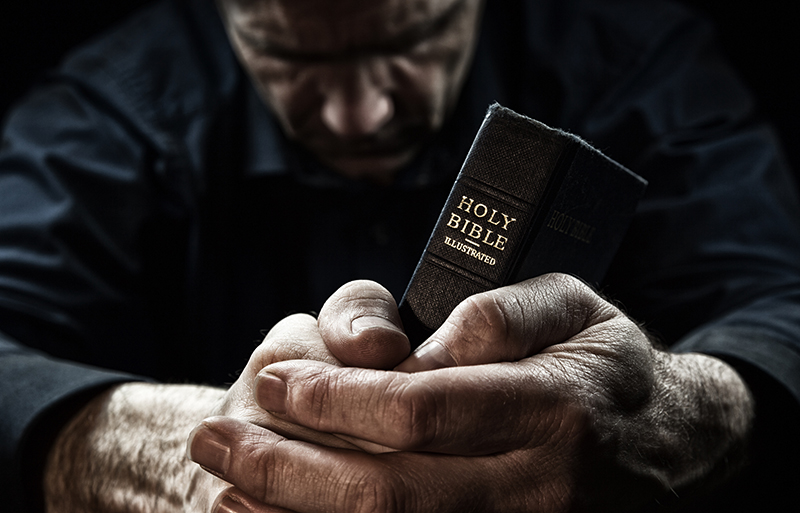 Man praying with holy bible in hands