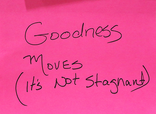 Pink post it with a handwritten note from A Revolution of Goodness, stating Goodness moves (it's not stagnant)