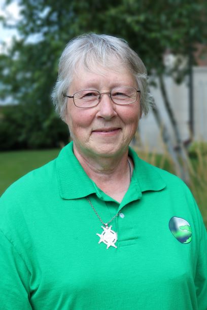 woman-gray-hair-green-shirt-glasses-medal